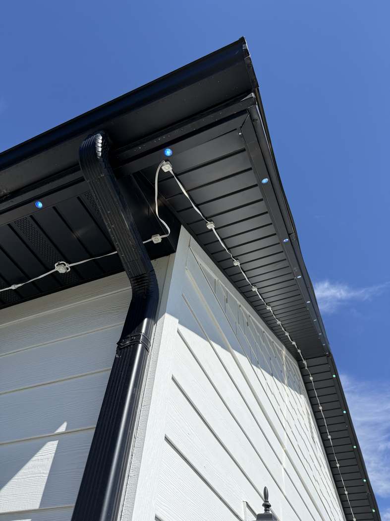 Roofline corner: exposed white wire on one plane, concealed black track on the other