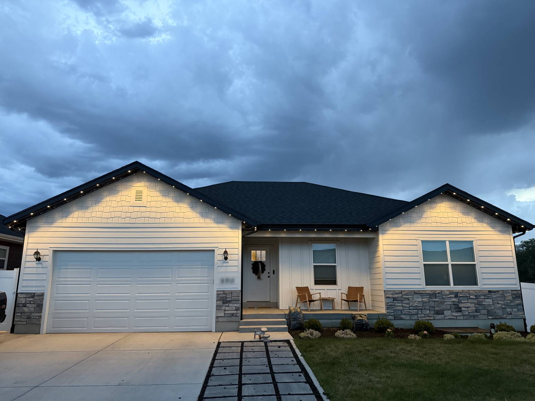 Full home elevation at dusk with warm white lights running every eave and gable