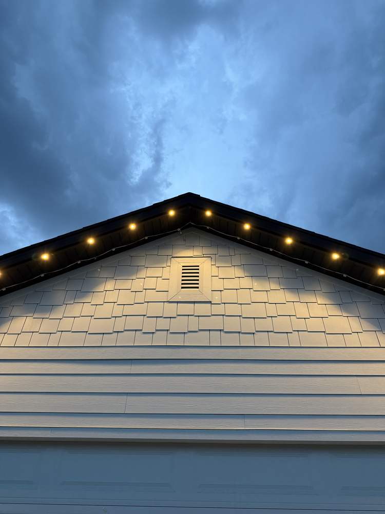 Lit gable peak at dusk, both rake runs meeting cleanly at the apex